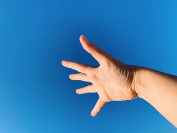 Cropped hand of person against blue sky