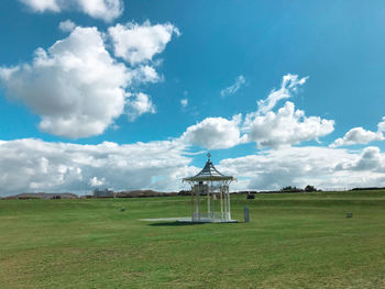 Windmill on field against cloudy sky