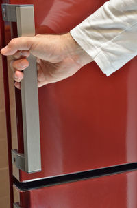 Hand on door handle of a red refrigerator