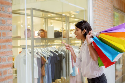 Woman with colorful shopping bags looking in store through window