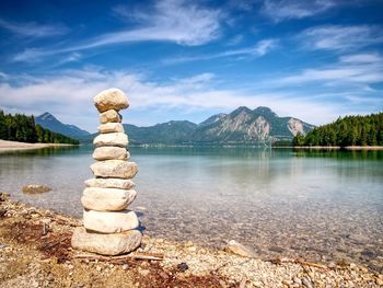 Stack of rocks in lake against sky