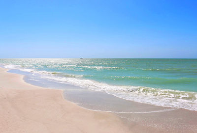 Scenic view of beach against clear blue sky