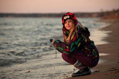 A 9 year old girl practices her photography and camera skills at the beach in the evening