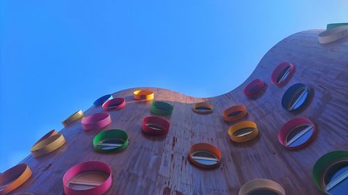 Low angle view of multi colored umbrellas against blue sky