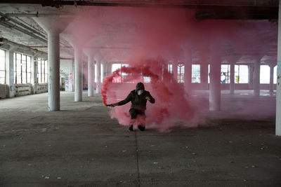 Full length of man holding distress flare in basement