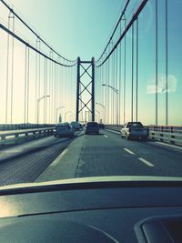 Cars on suspension bridge against clear sky