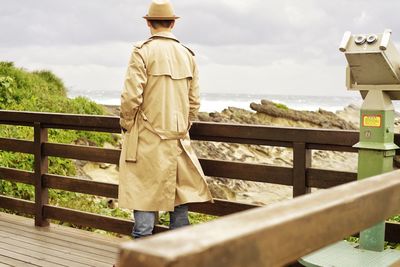 Rear view of man standing on railing