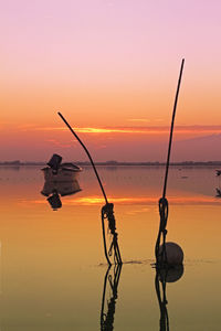 Silhouette fishing rod on beach against sky during sunset