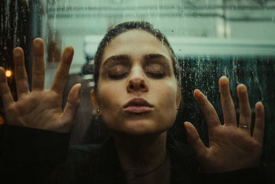 Close-up of young woman touching glass window