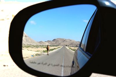 Reflection of camel and road on car side-view mirror