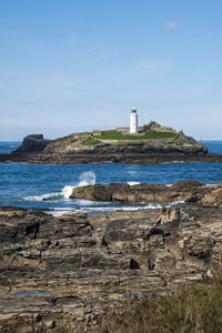 Lighthouse by sea against sky