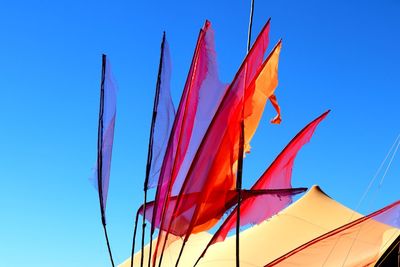 Low angle view of flags against clear blue sky