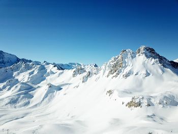 Scenic view of snowcapped mountains against clear blue sky