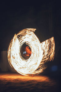 Blurred motion of man against illuminated fire at night