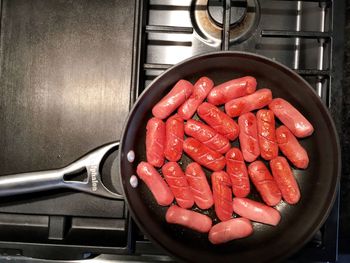 Directly above shot of sausages cooking in pan on gas stove burner