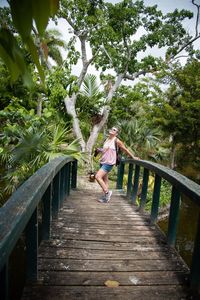 Woman standing on footbridge amidst trees