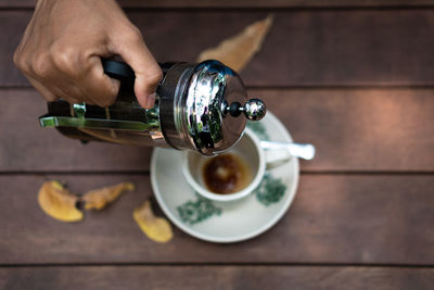 Midsection of person having coffee cup on table