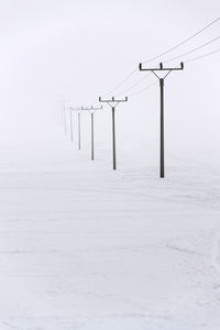 Snow covered poles against sky