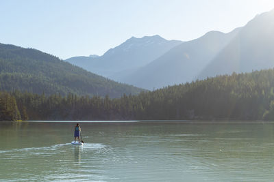 Pregnant woman paddleboarding on peaceful mountain lake