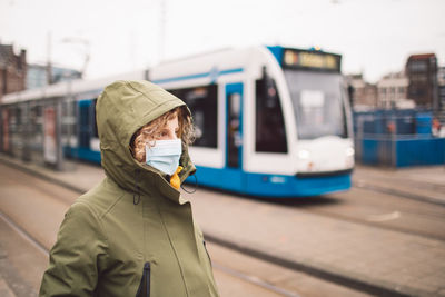 Woman wearing a mask standing on tram track in city