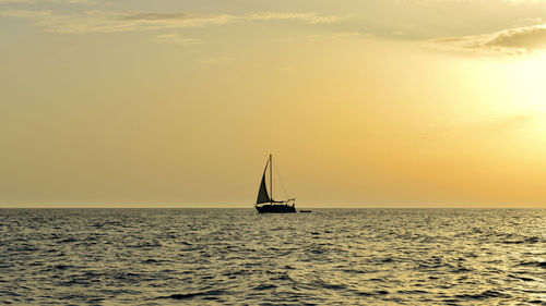 Sailboat sailing on sea against sky during sunset