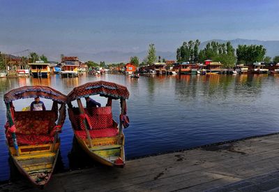 Boats moored by pier on lake against sky