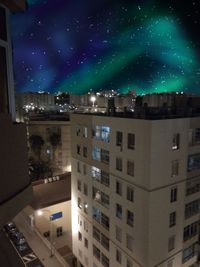 Illuminated buildings in town against sky at night