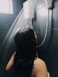 Rear view of shirtless woman in bathroom