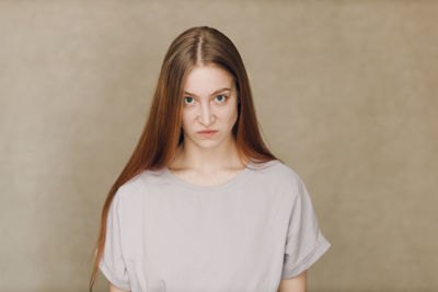 Portrait of young woman standing against wall