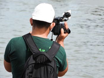 Rear view of man photographing against sea