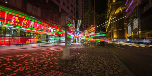 Light trails on street amidst illuminated buildings in city at night