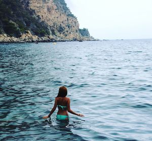 Full length of shirtless in sea against sky