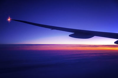 Silhouette airplane wing against sky during sunset