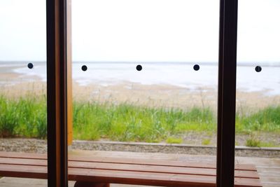 Scenic view of field seen through glass window