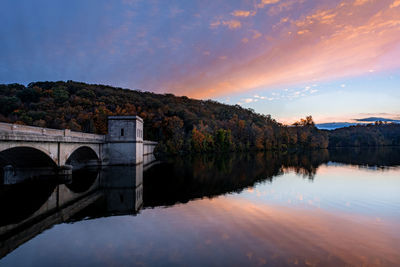 Arch bridge over river against sky during sunset