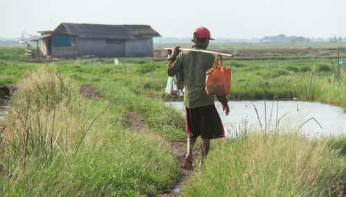 Rear view of woman walking on grassy field