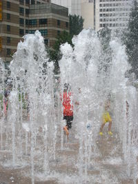 Water splashing in swimming pool against buildings in city