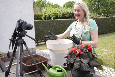 Middle aged woman transplant seedlings of cherry tomatous into a large pot