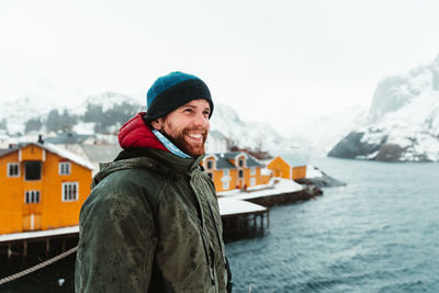 Portrait of smiling man in snow against sky