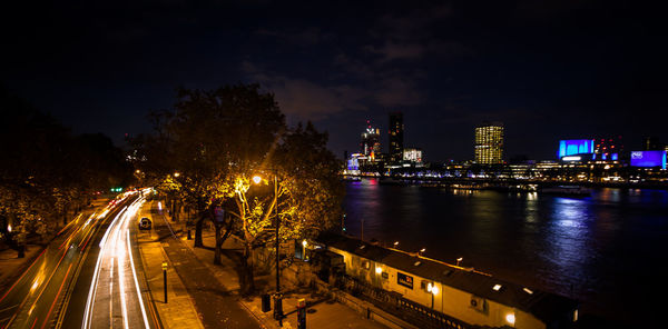 Illuminated bridge over river in city at night