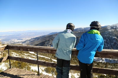 Rear view of friends standing by railing at observation point