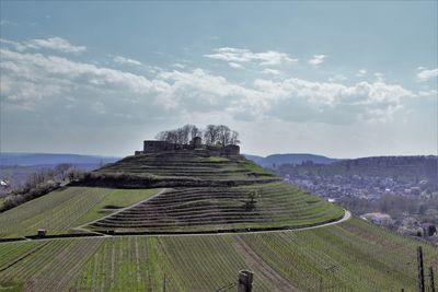 Stone structure on landscape against cloudy sky