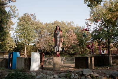 Full length of woman standing on built structure against trees