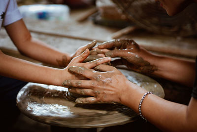 Artist teaching boy during pottery class