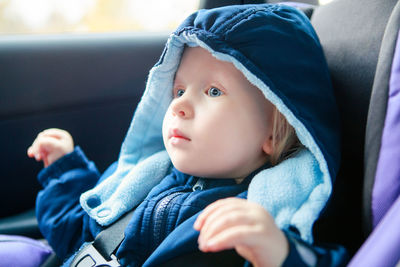 Baby infant sitting in car seat. kid in outwear clothes in carsit fastened with seatbelt. 