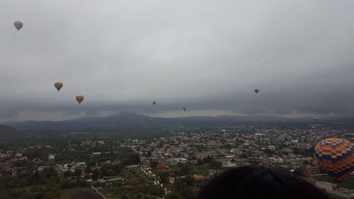 Hot air balloons flying in city against sky