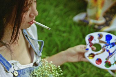 Woman smoking cigarette while holding color palette