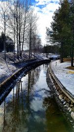 Canal amidst bare trees against sky during winter