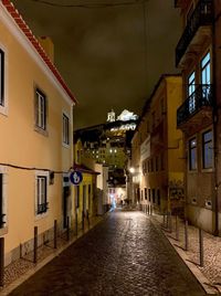 Empty alley amidst buildings at night