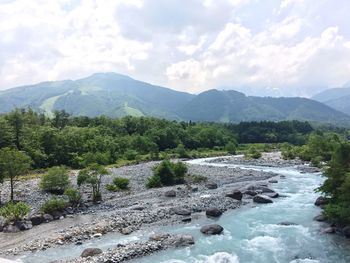 Scenic view of river by mountains against sky